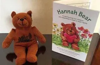 Brown teddy bear beside a coloring book titled 