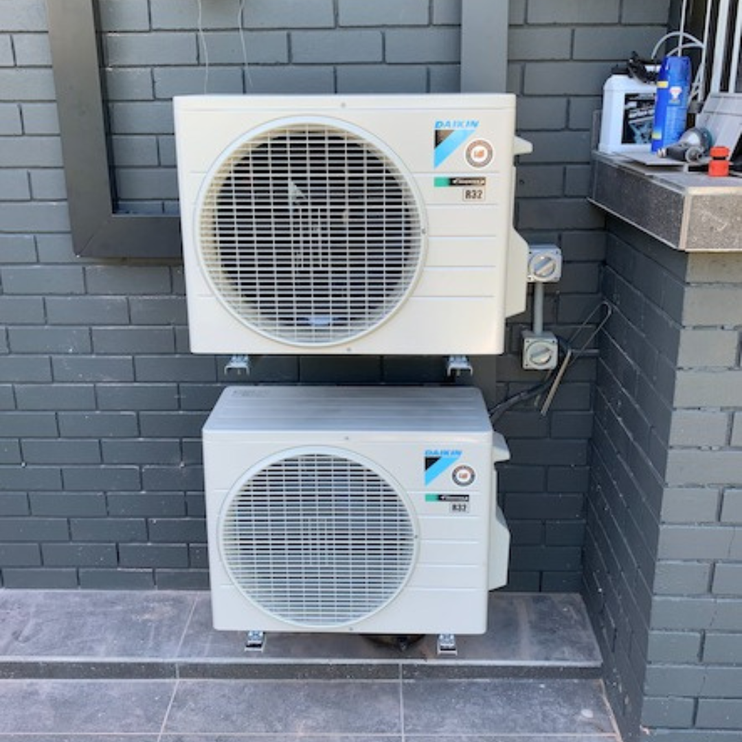 Two outdoor Daikin units installed on a brick wall.