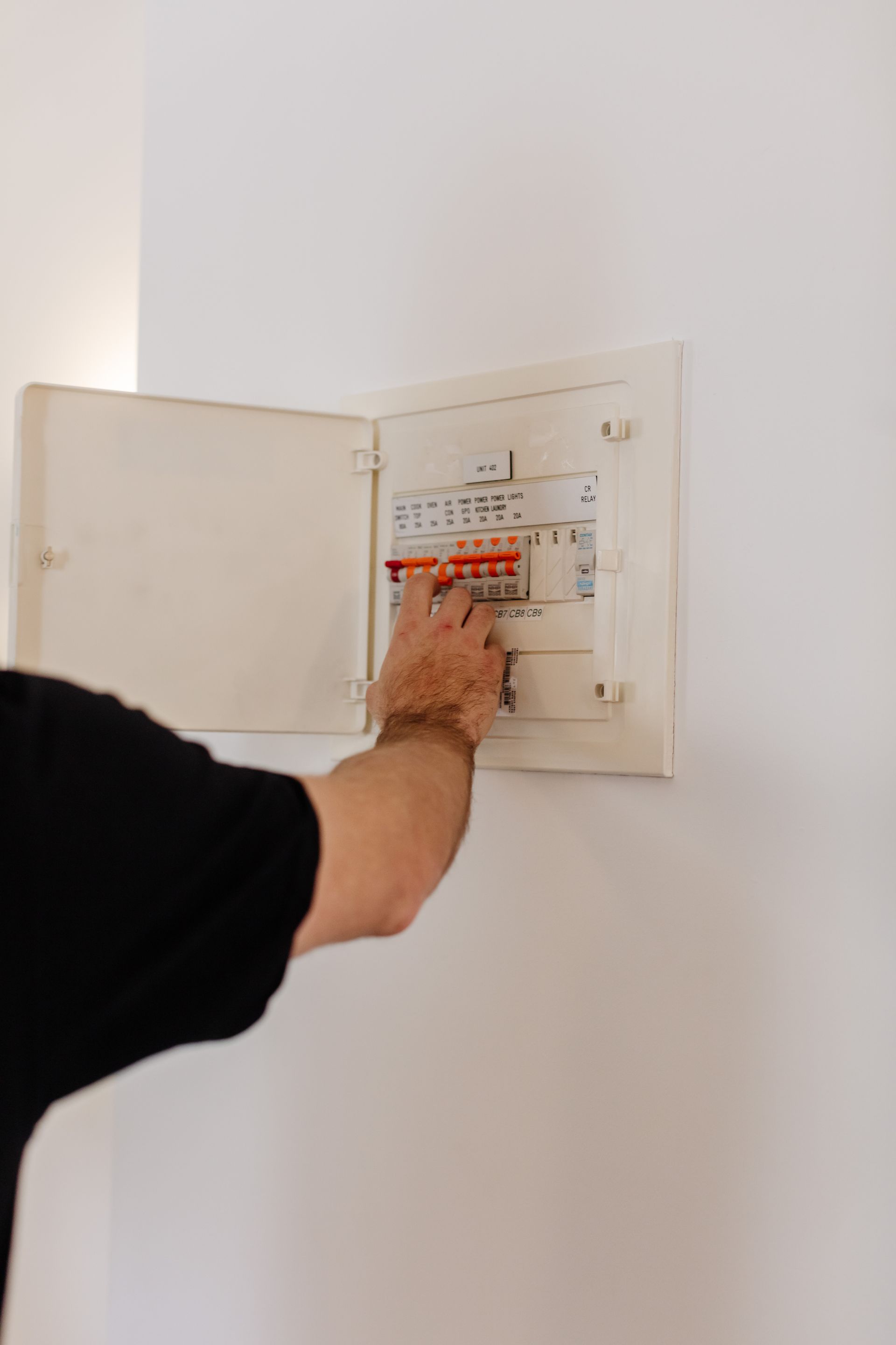 An electrical switchboard being serviced by a team member from Lakeside Air & Electrical.