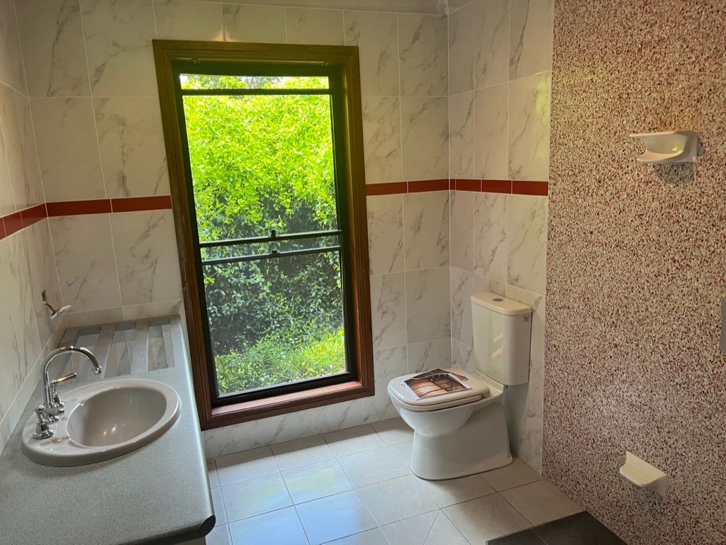 Modern bathroom with wood panel walls, a glass shower, black fixtures, and a view of the ocean.