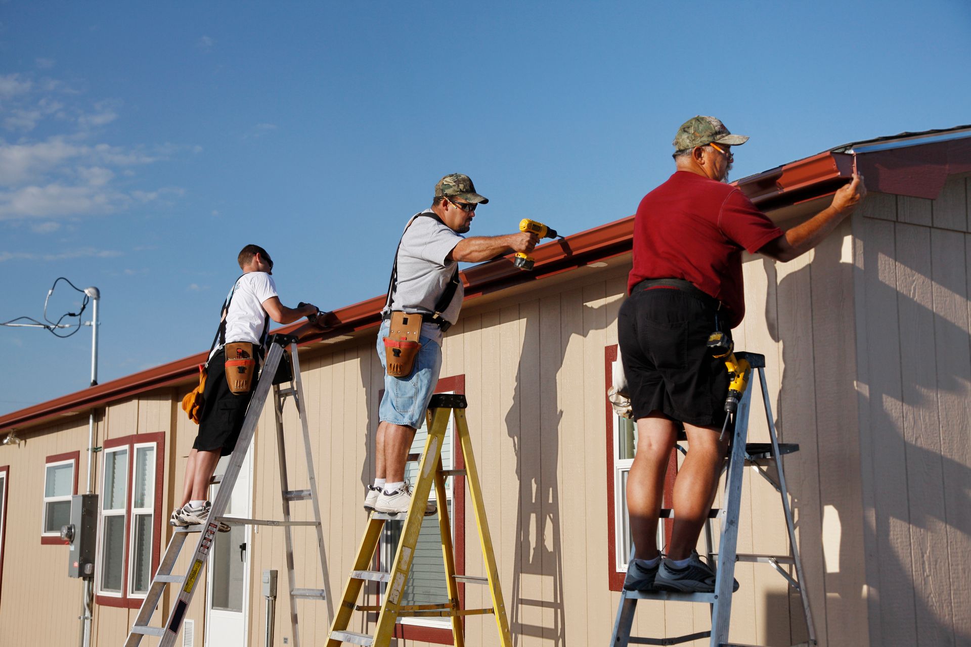 Three men are working on the roof of a house