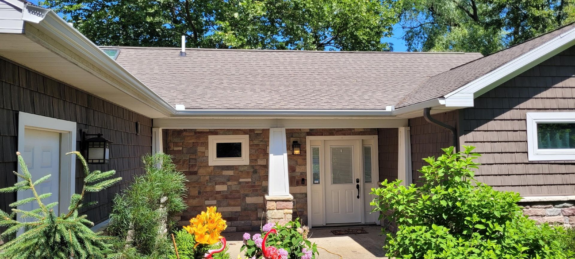 The front of a house with a porch and flowers in front of it.