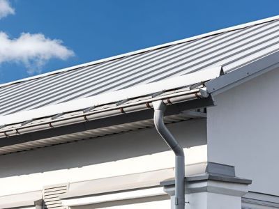 A white house with a metal roof and gutter.