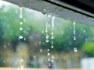 Rain is falling from the roof of a building.