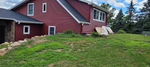A large red house is sitting on top of a grassy hill.