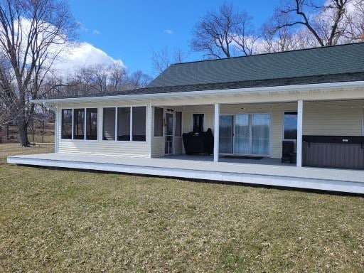 A house with a screened in porch and a hot tub in the backyard.