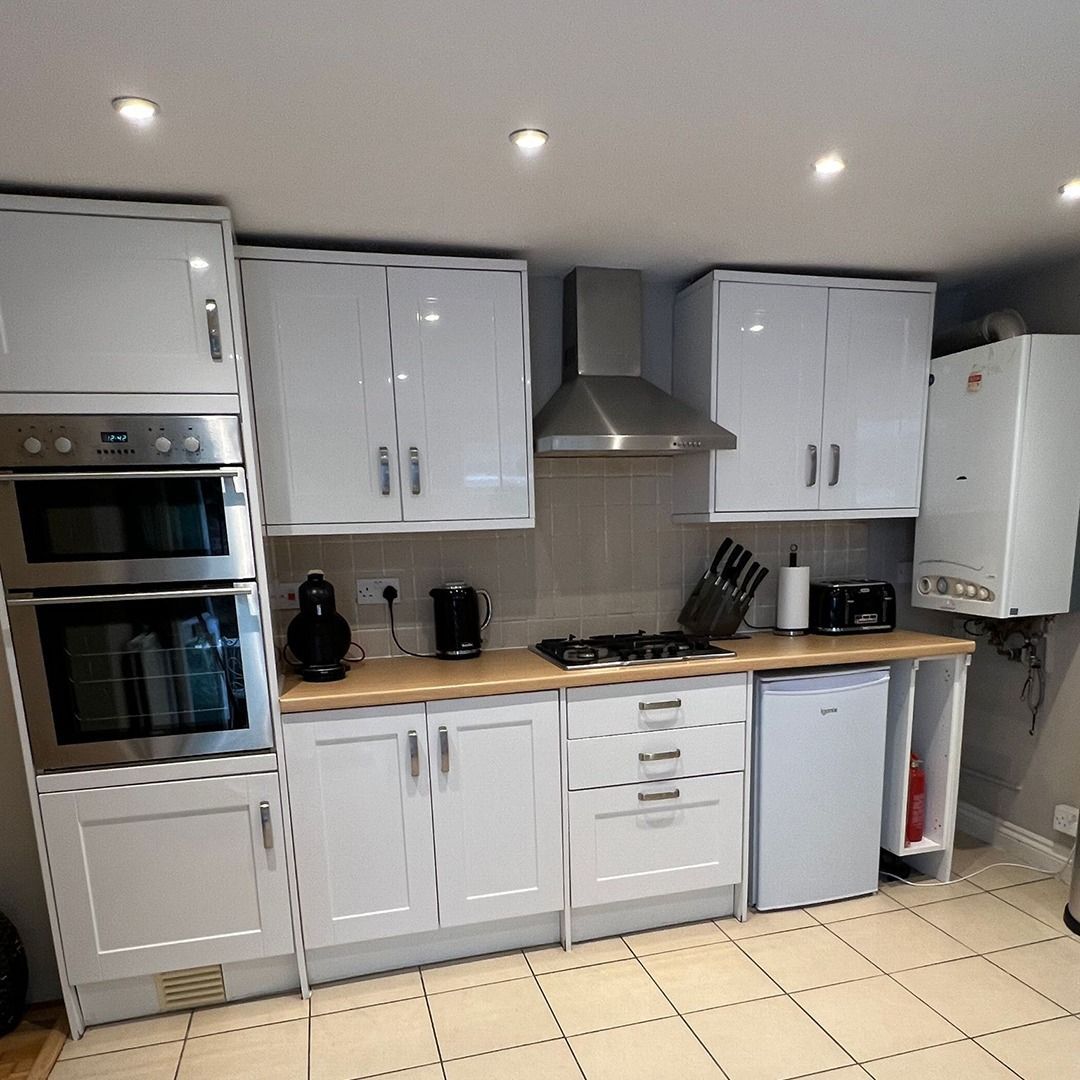 A person wearing yellow gloves is cleaning a window with a sponge.