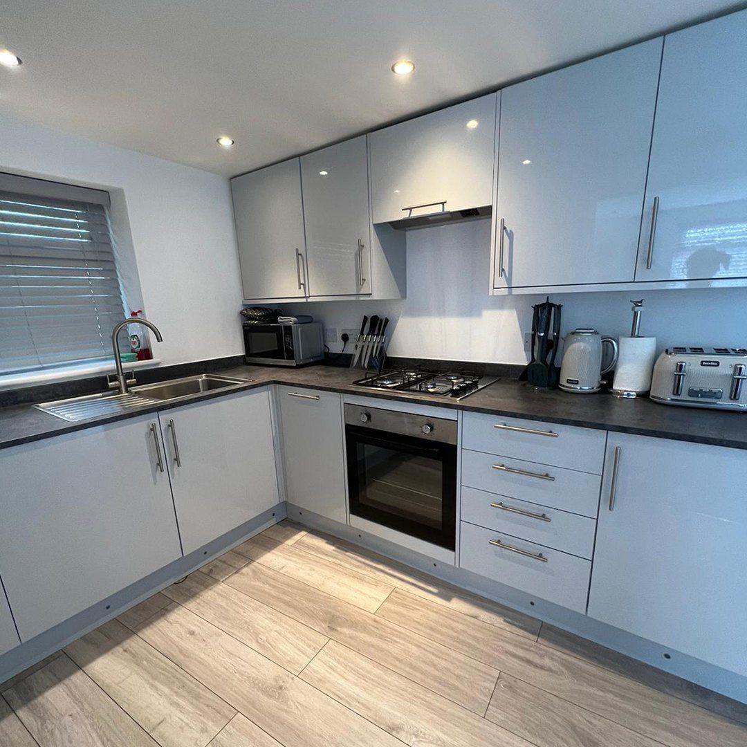 A person is cleaning a kitchen sink with a cloth and spray bottle.