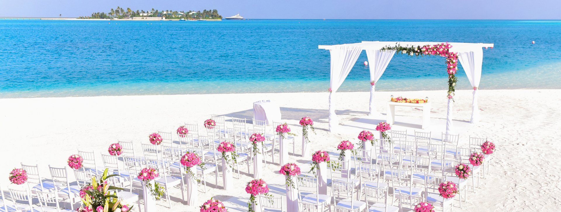 A wedding ceremony is taking place on a tropical beach.