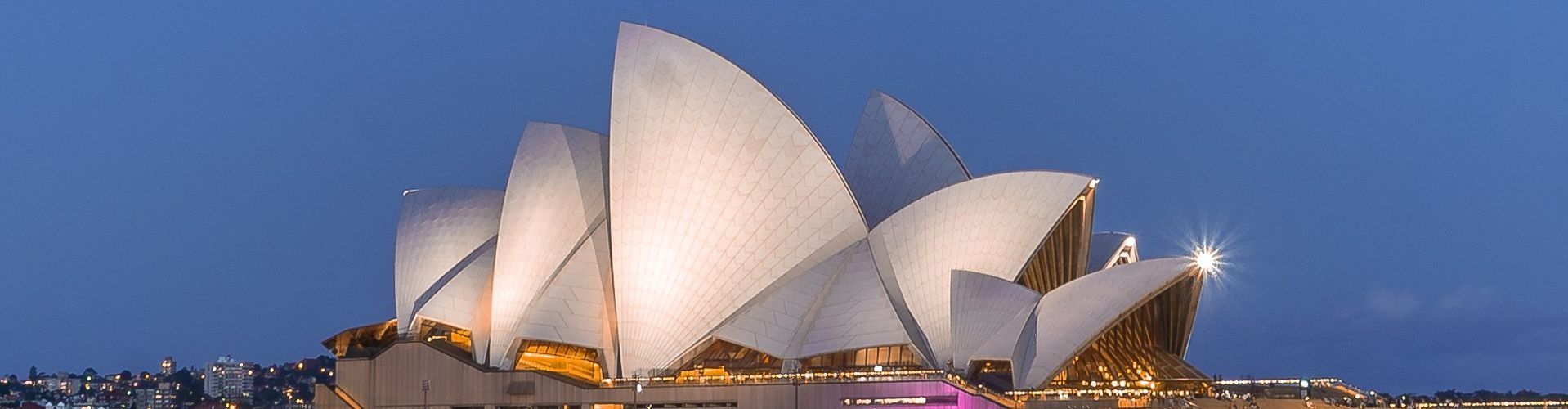 The opera house in sydney is lit up at night.