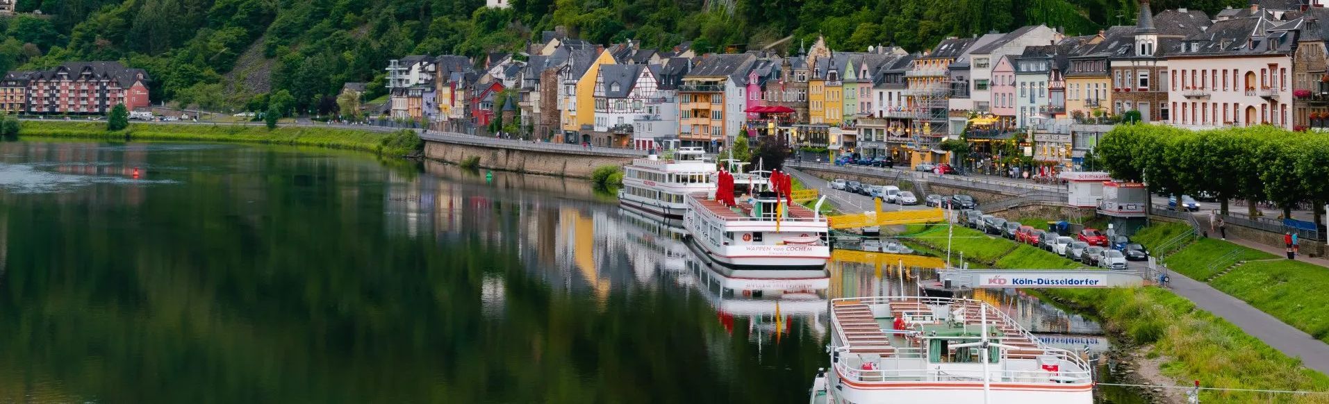 A boat is docked in front of a small town on the shore of a lake.