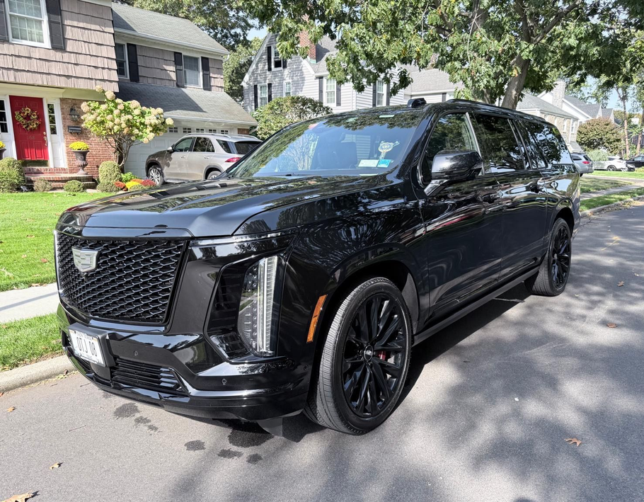 Black Cadillac Escalade SUV parked on a residential street.