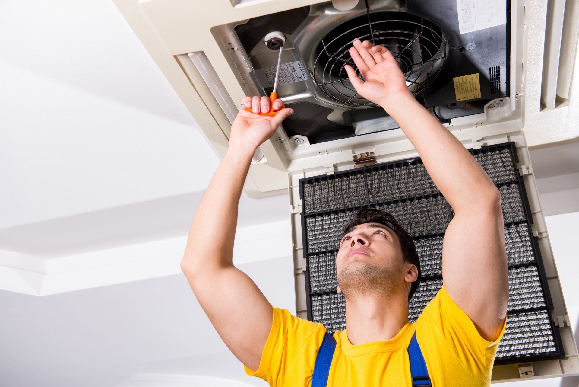 Hvac technician wearing yellow shirt repairing Ac