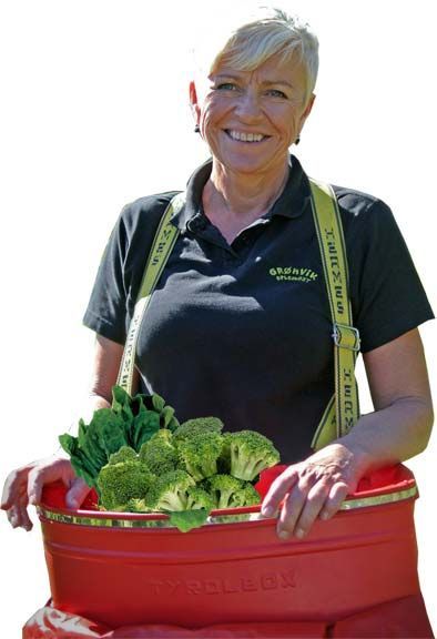 A woman in a black shirt is holding a red bucket full of vegetables.