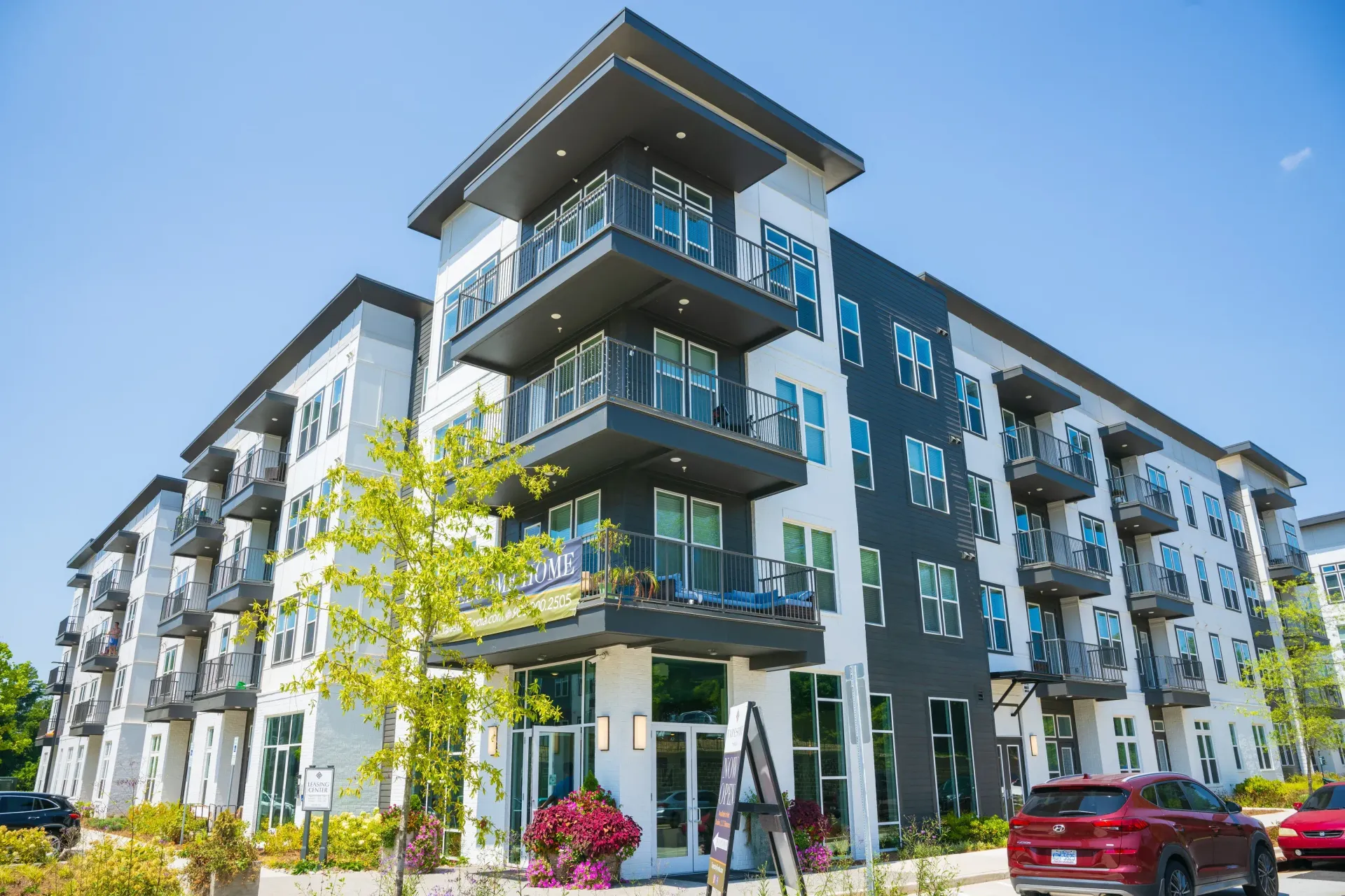 Modern apartment building with balconies, gray and white facade, sunny day.