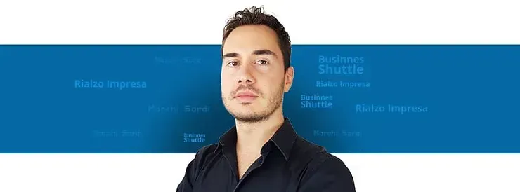 Un uomo con una camicia nera è in piedi davanti a un muro blu.
