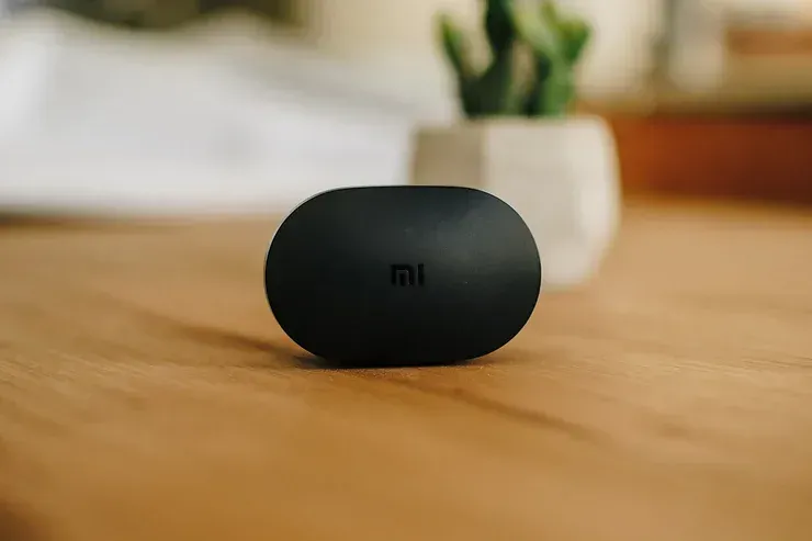 Un paio di auricolari Xiaomi sono appoggiati su un tavolo di legno.