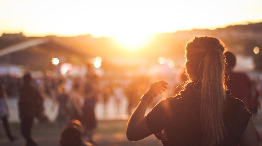 Una donna è in piedi di fronte a una folla di persone che guardano il tramonto.