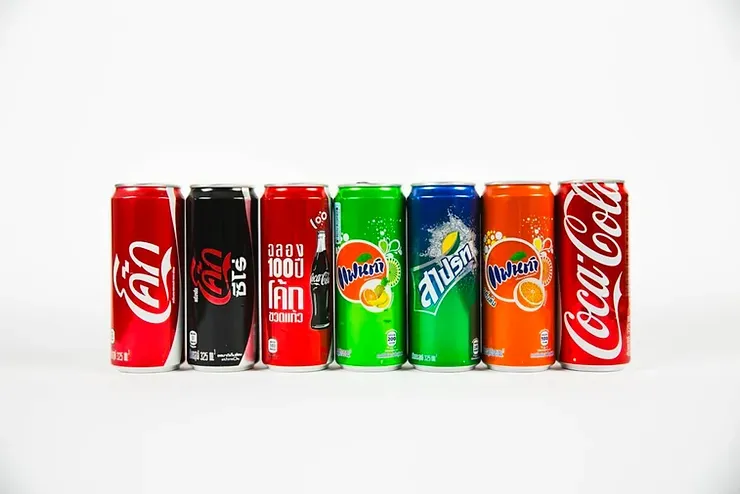 Una fila di lattine di Coca-Cola, Fanta, Sprite e Dr. Pepper allineate.
