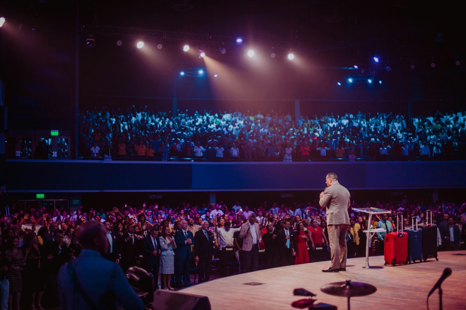 A man is standing on a stage in front of a crowd of people.