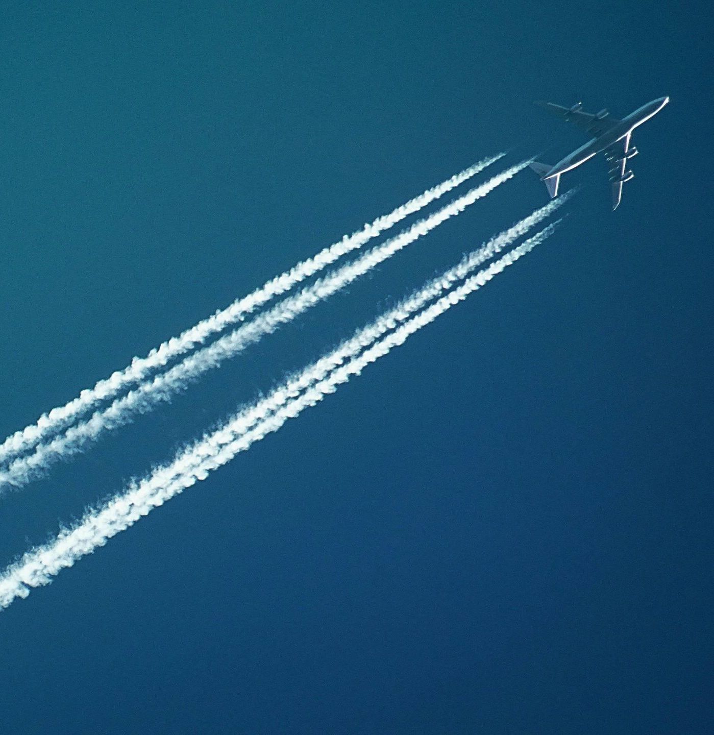 Un aereo che vola attraverso un cielo azzurro con scie di fumo