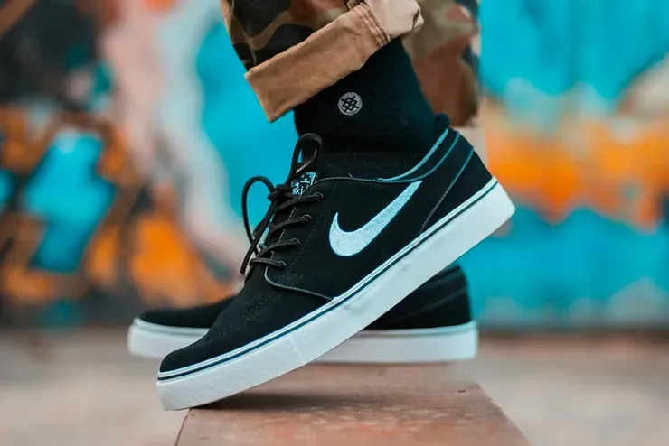 Una persona indossa un paio di scarpe da ginnastica Nike nere e bianche.
