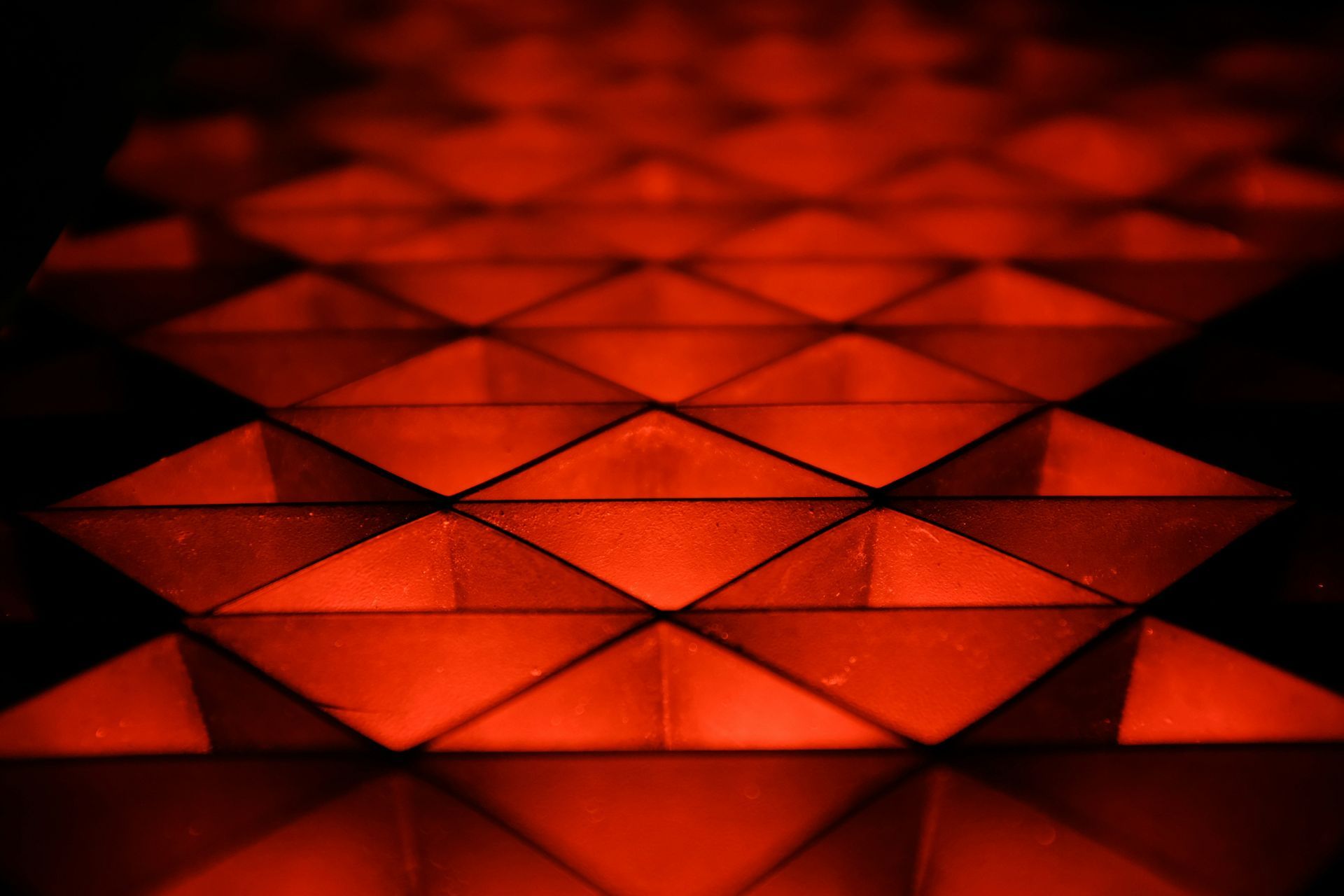 A close up of a pattern of red triangles in a dark room.