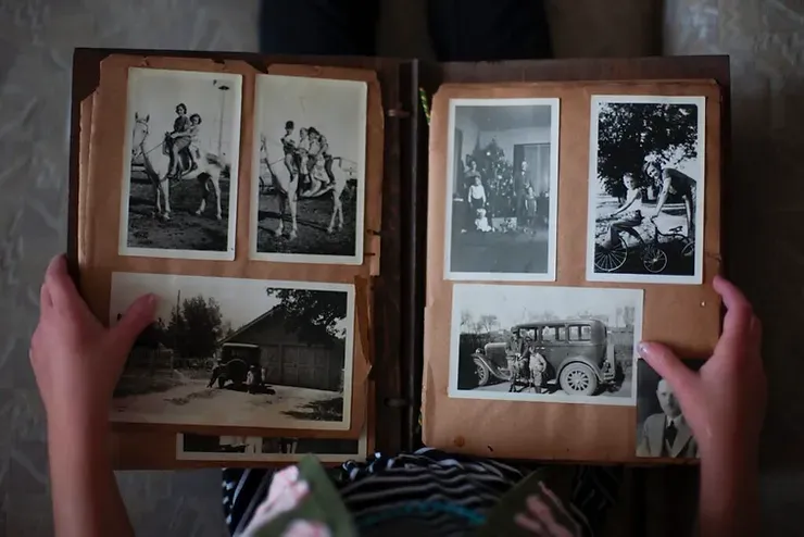 Una persona tiene in mano un album fotografico pieno di vecchie foto in bianco e nero.