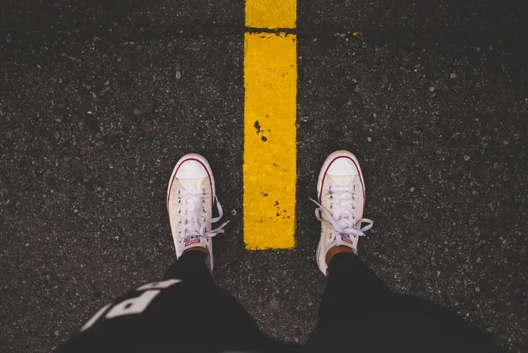 Una persona è in piedi accanto a una linea gialla sulla strada.