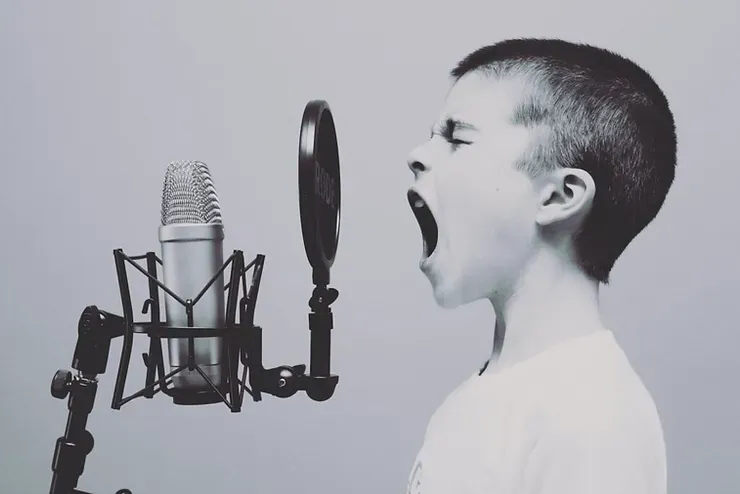 Un ragazzino canta in un microfono in una foto in bianco e nero.