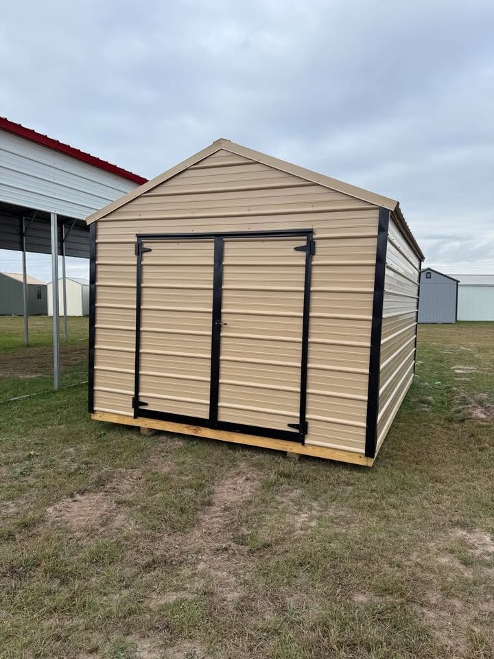Tan metal storage shed with black door frames, outdoors.