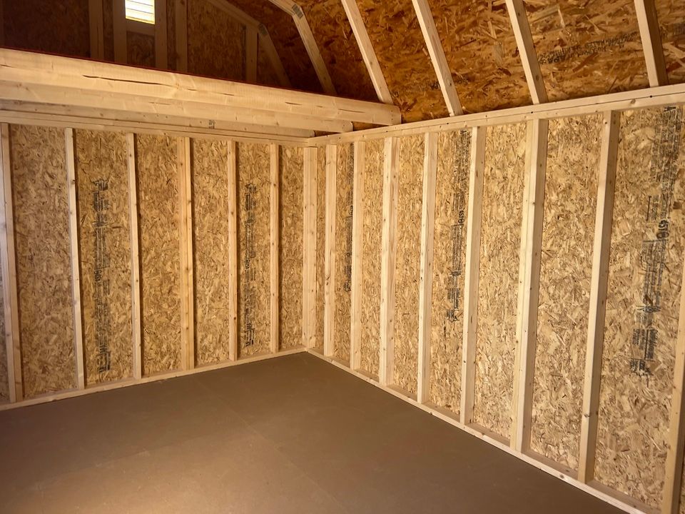 Interior of a small wooden shed with exposed wood framing and particle board walls.