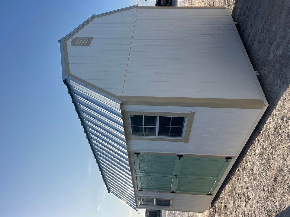 White shed with metal roof and green shutters.