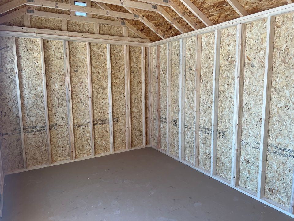 Interior view of a small shed with unfinished wooden walls, ceiling, and floor.