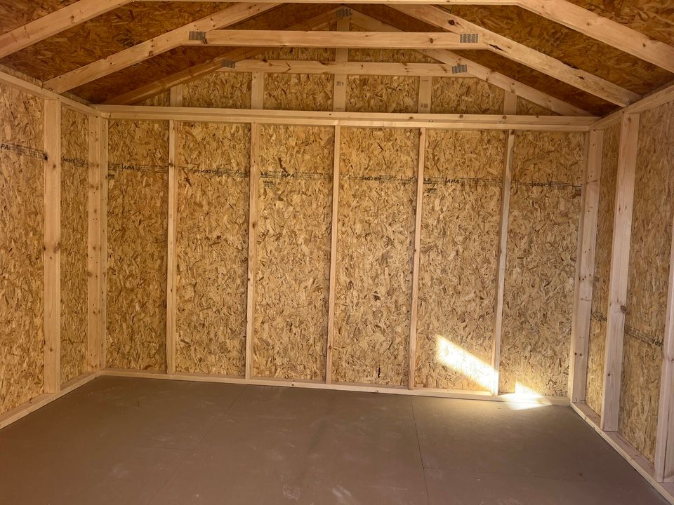 Interior view of a wooden shed with oriented strand board walls and a sloped ceiling.