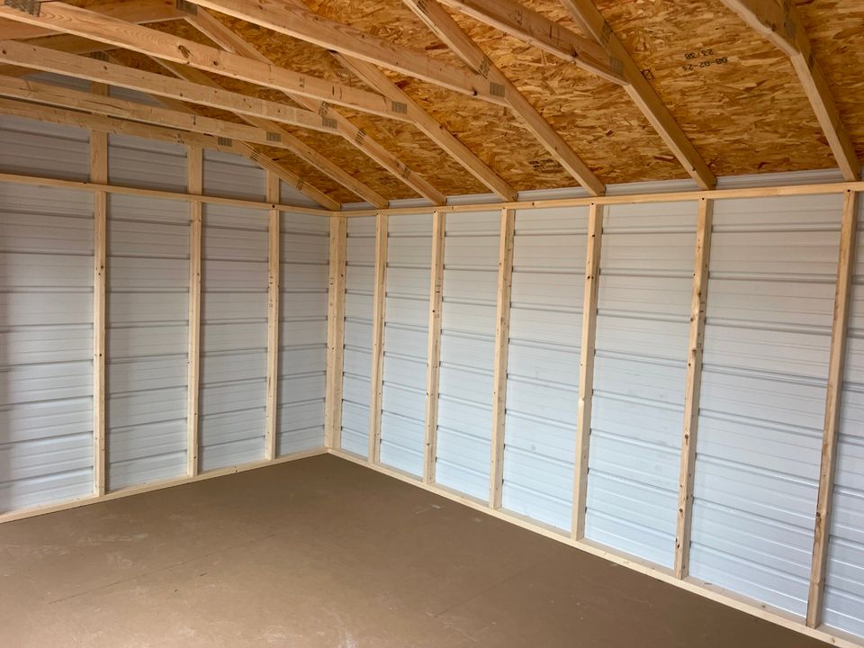 Interior of a shed with wood frame, light-colored metal walls, and a concrete floor.