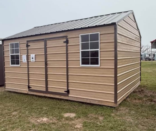 Tan metal shed with dark brown trim, windows, and double doors; sits on grass.
