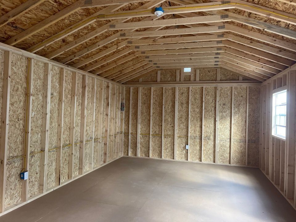 Interior of a new shed with wooden walls, roof, and concrete floor; a window is visible.