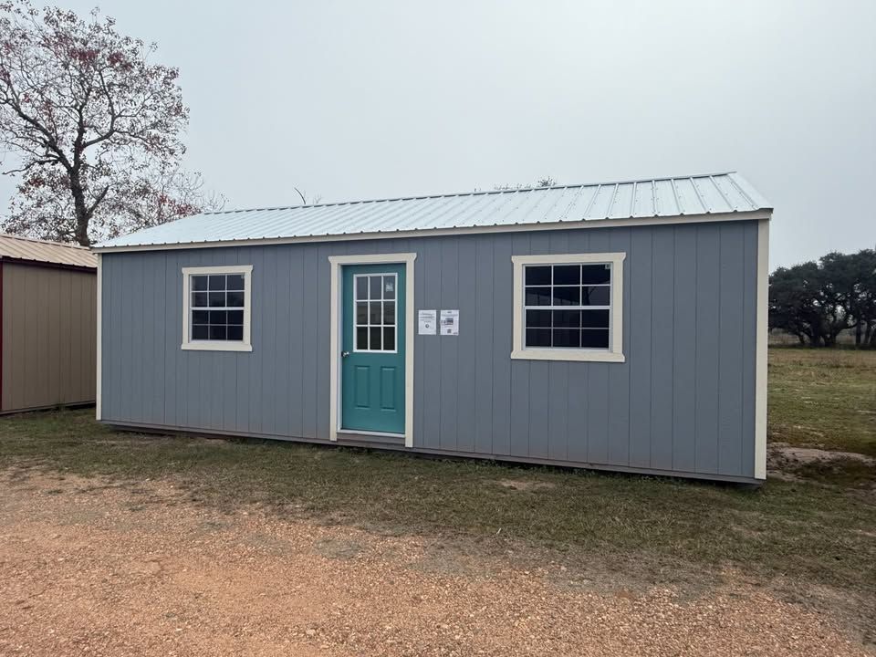 Blue storage shed with white trim, teal door, two windows, and metal roof.