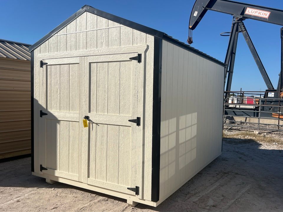 Tan shed with black trim and double doors; outdoors with an oil pump in the background.