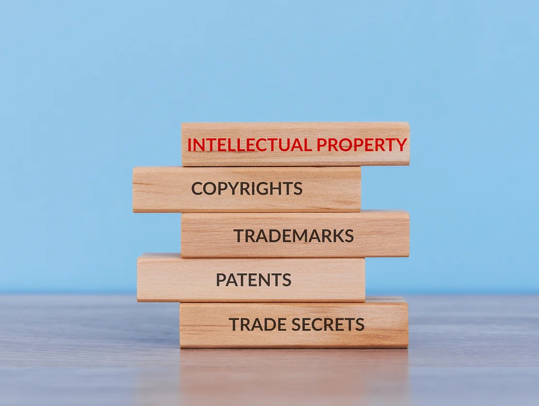 A stack of wooden blocks with the words intellectual property copyrights trademarks patents and trade secrets written on them.