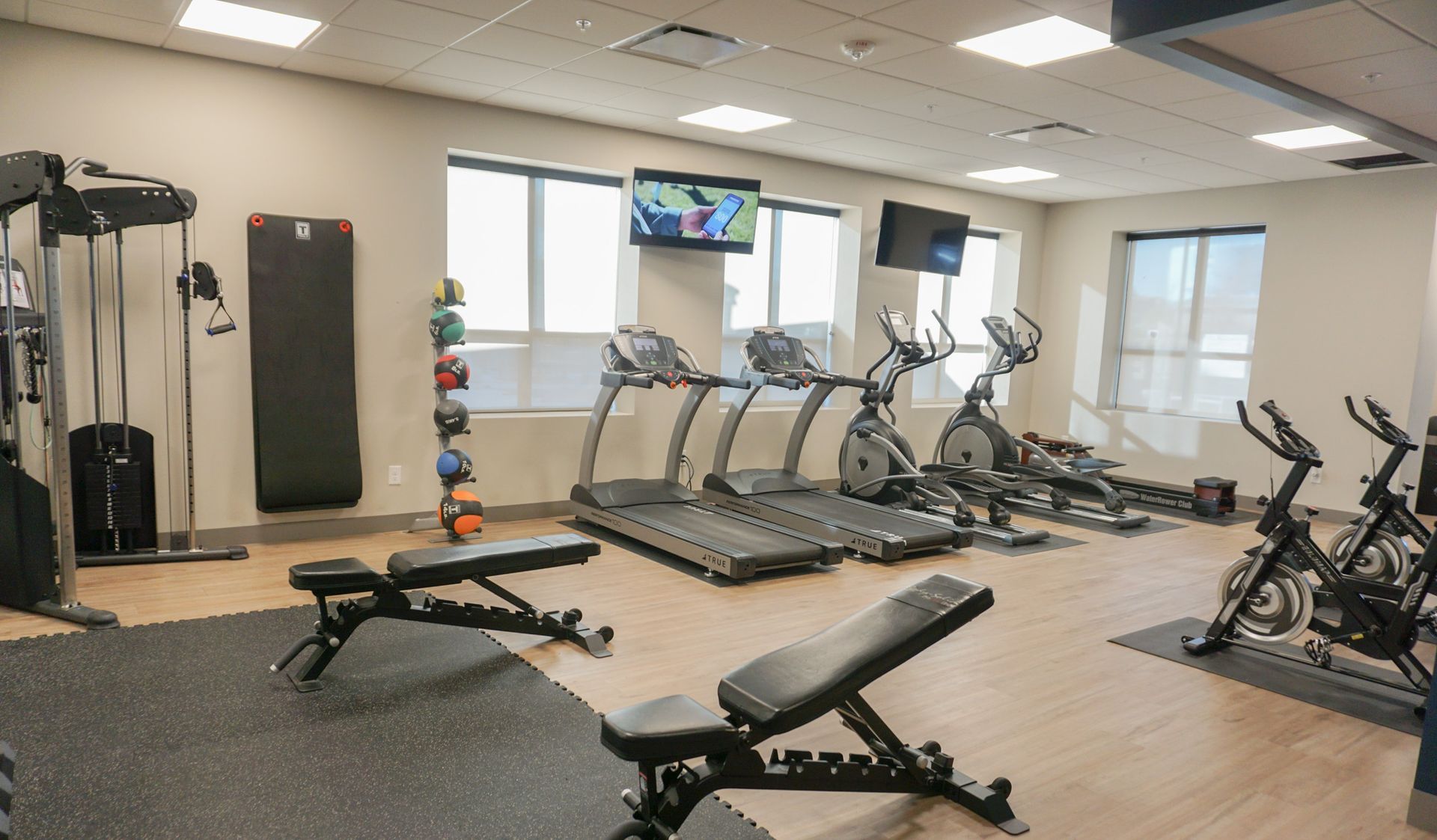 Gym with treadmills, elliptical machines, weights, and exercise equipment.