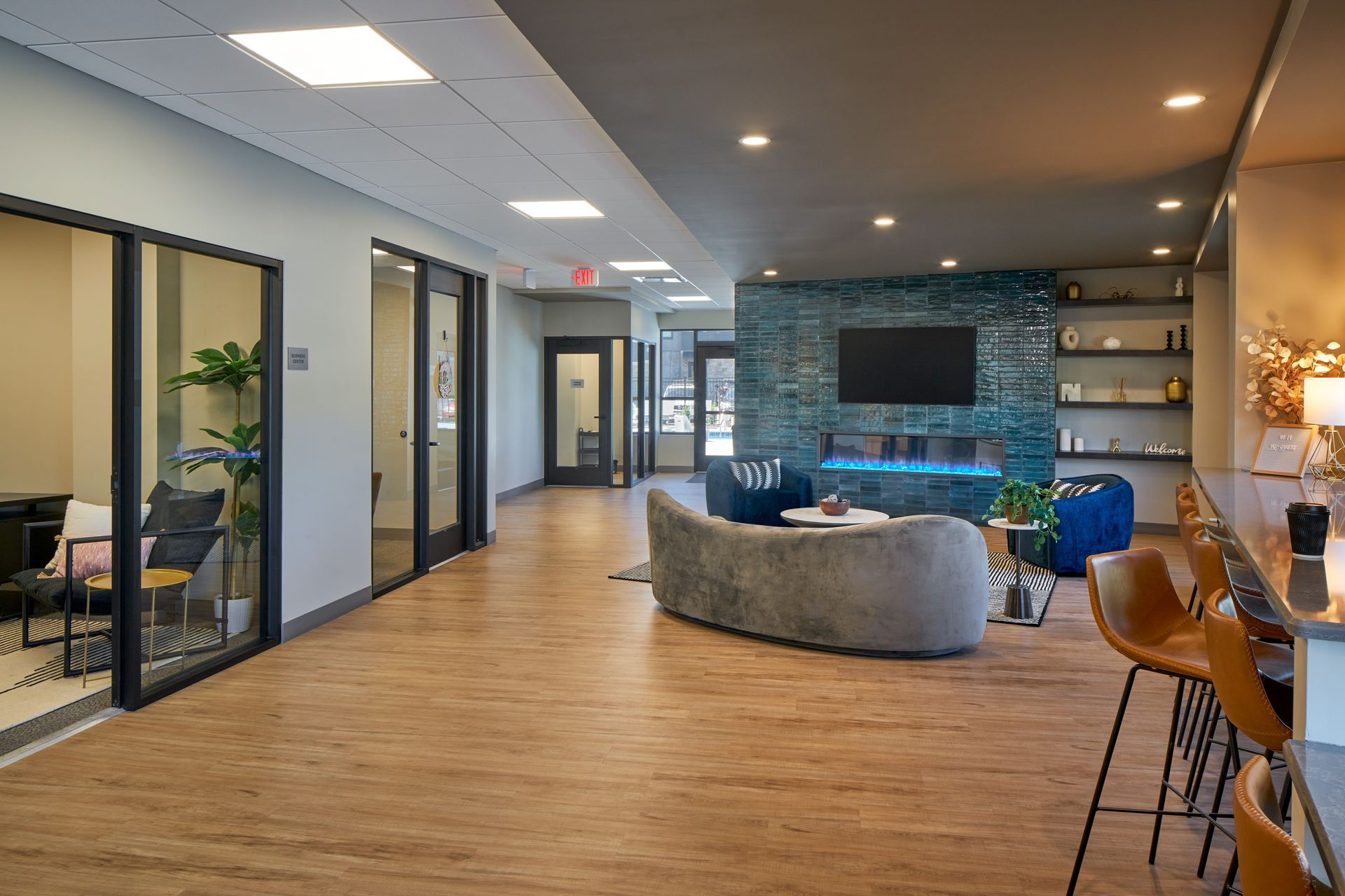 Spacious modern lounge with fireplace, seating, bar, and glass-walled offices.