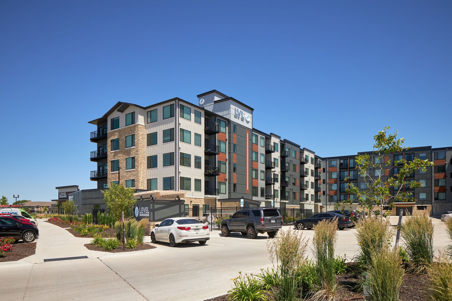 Apartment building with cars parked out front on a sunny day.