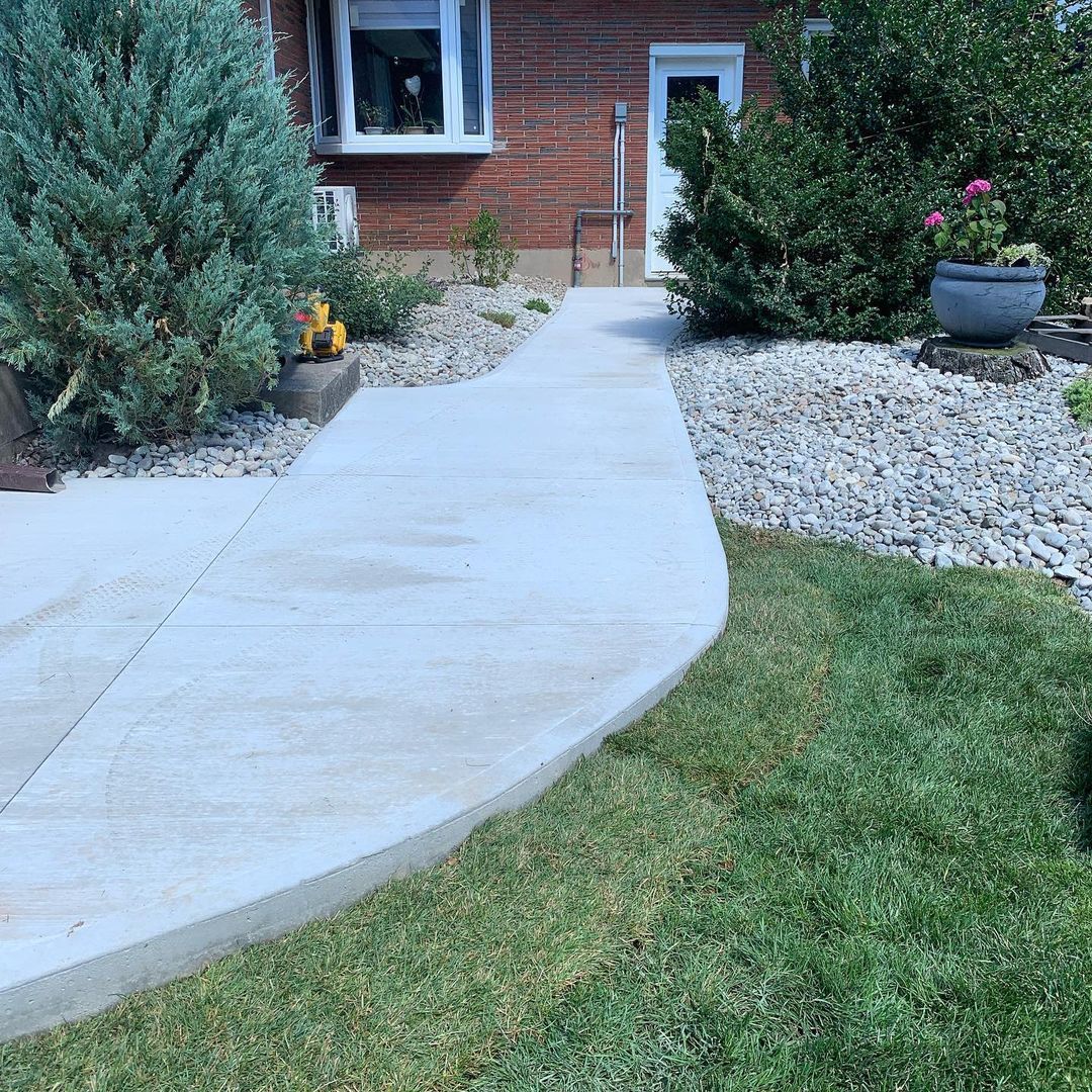 A brick house with a concrete walkway leading to it.