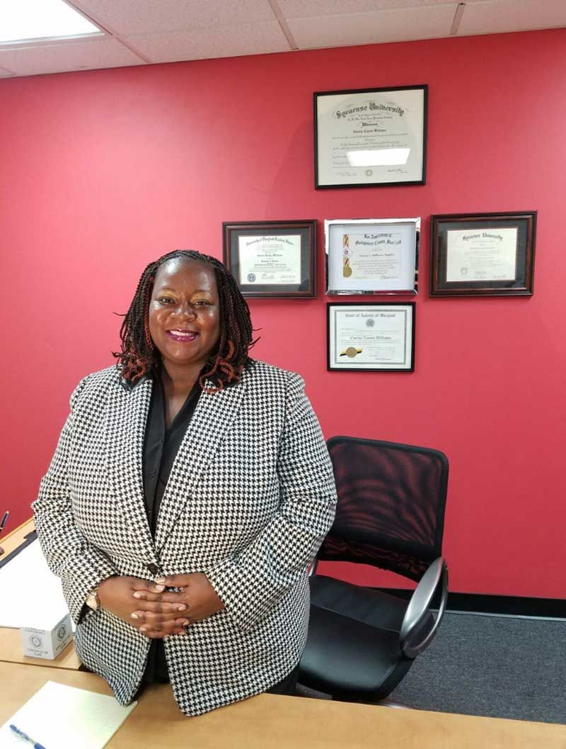 A woman in a purple jacket and scarf is smiling for the camera.