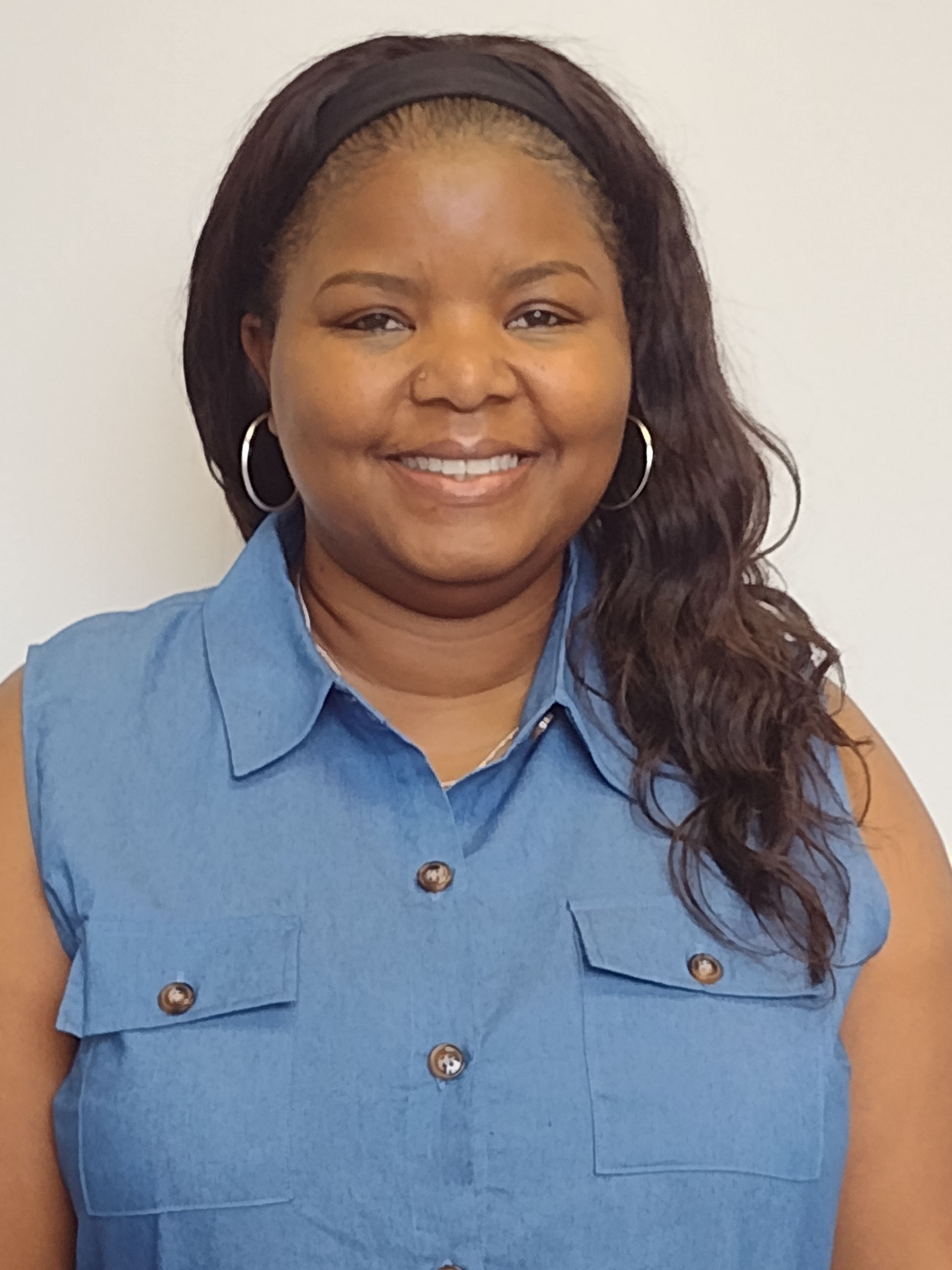 A woman in a blue shirt is smiling for the camera