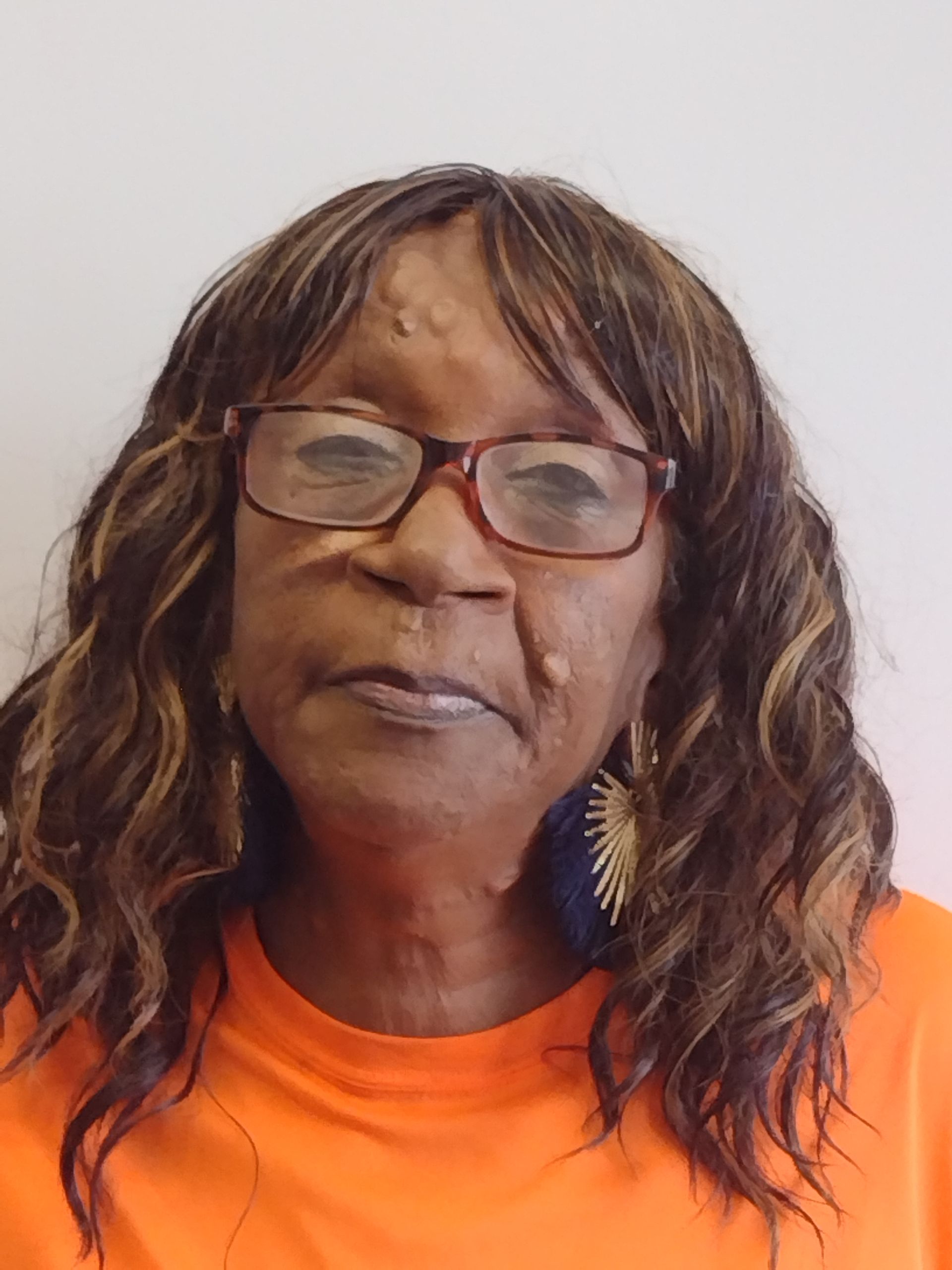 A woman wearing glasses and earrings is wearing an orange shirt