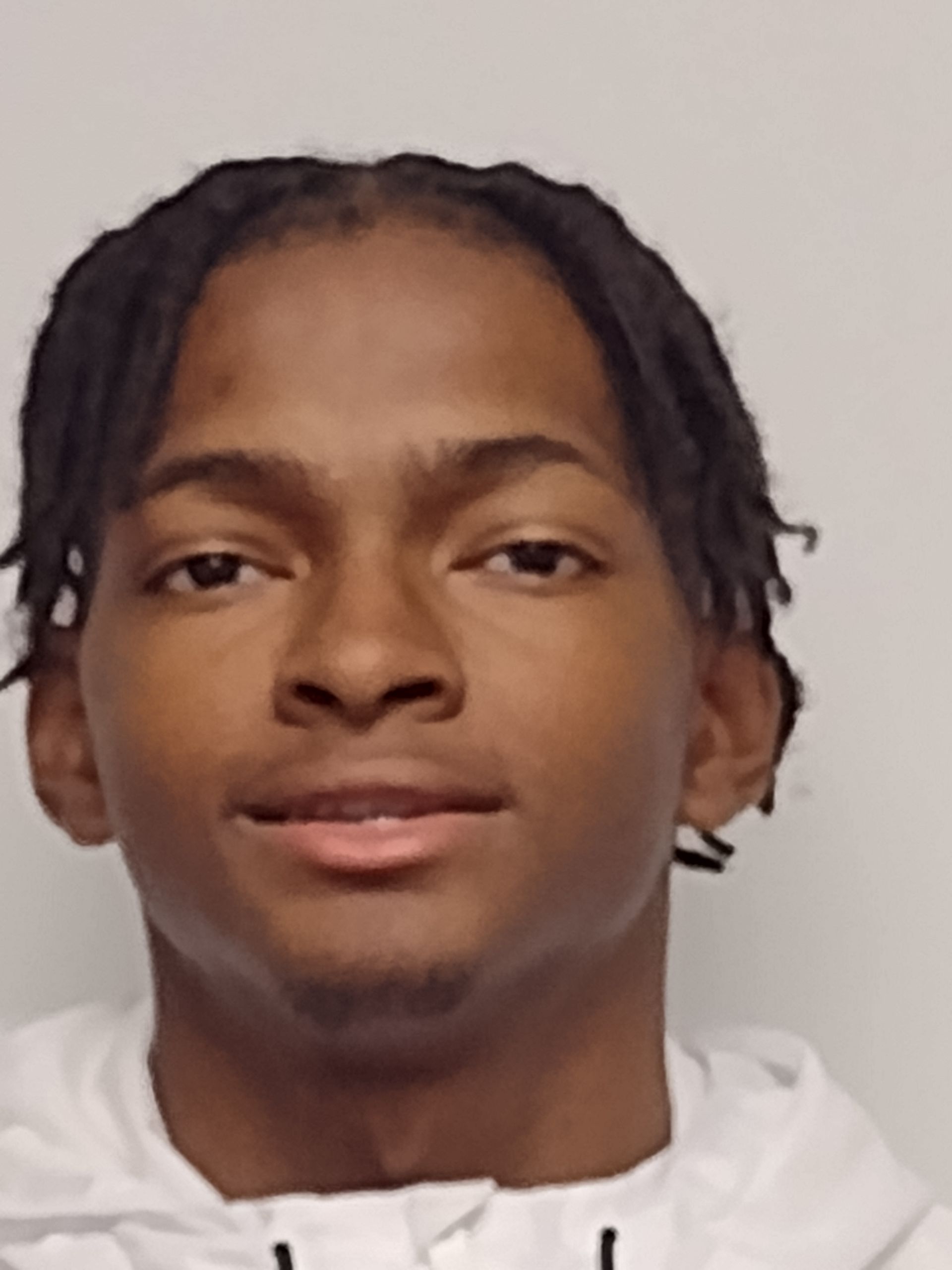 A young man with dreadlocks is wearing a white hoodie.