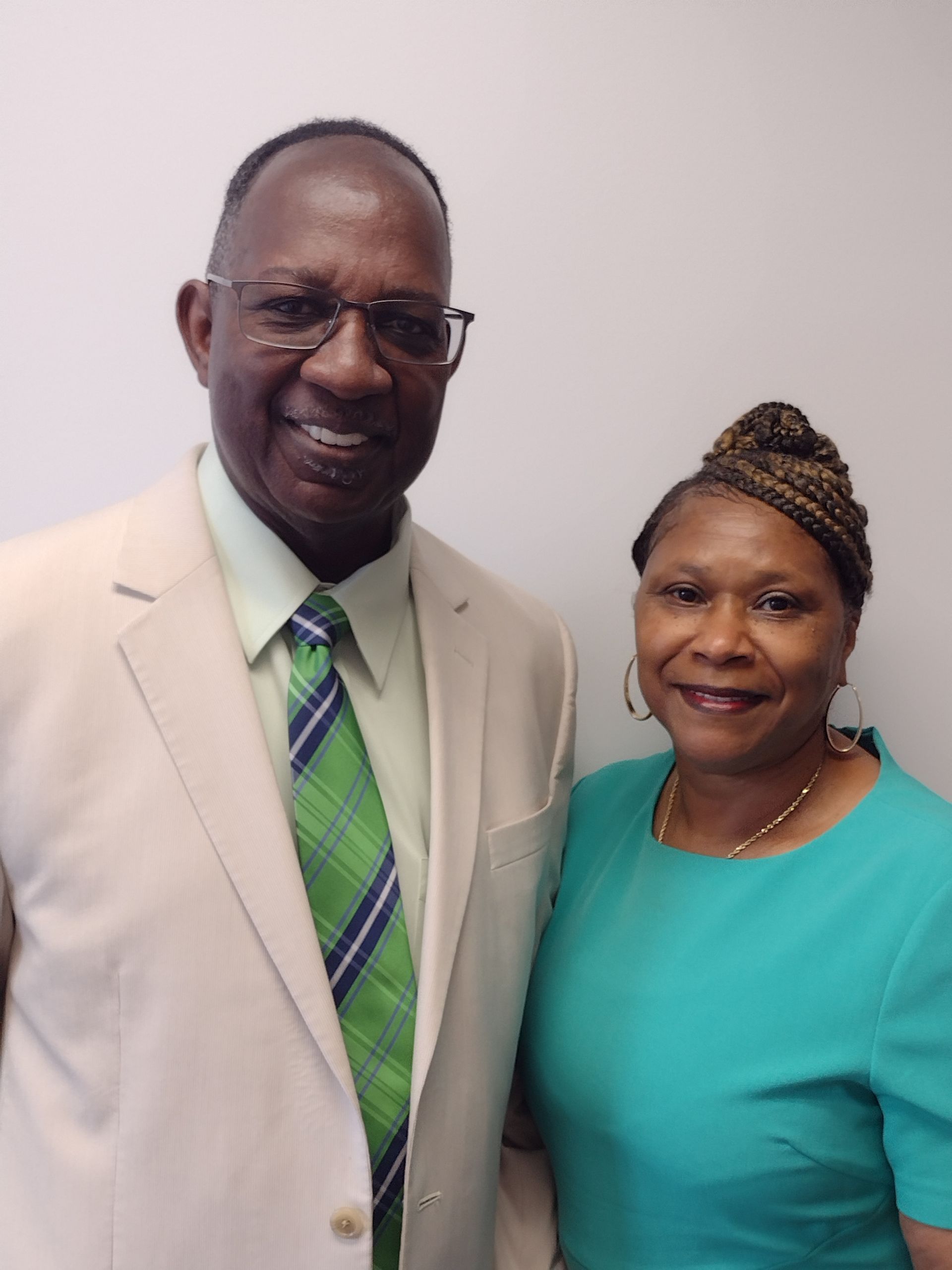 A man in a suit and tie is standing next to a woman in a blue dress.